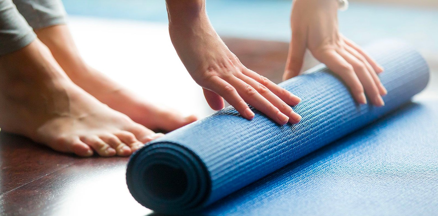 Femme qui etale un tapis de gym exercices de kine post partum| IK Paris