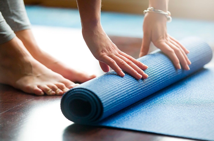 Femme qui etale un tapis de gym exercices de kine post partum| IK Paris