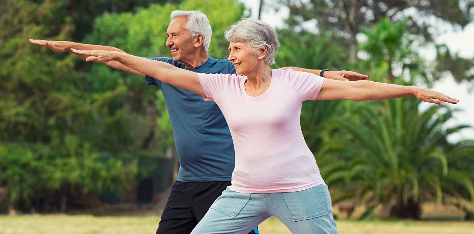 Couple de 50 ans faisant des exercices dans un park - apres 50 ans ameliorer equilibre | IK Paris